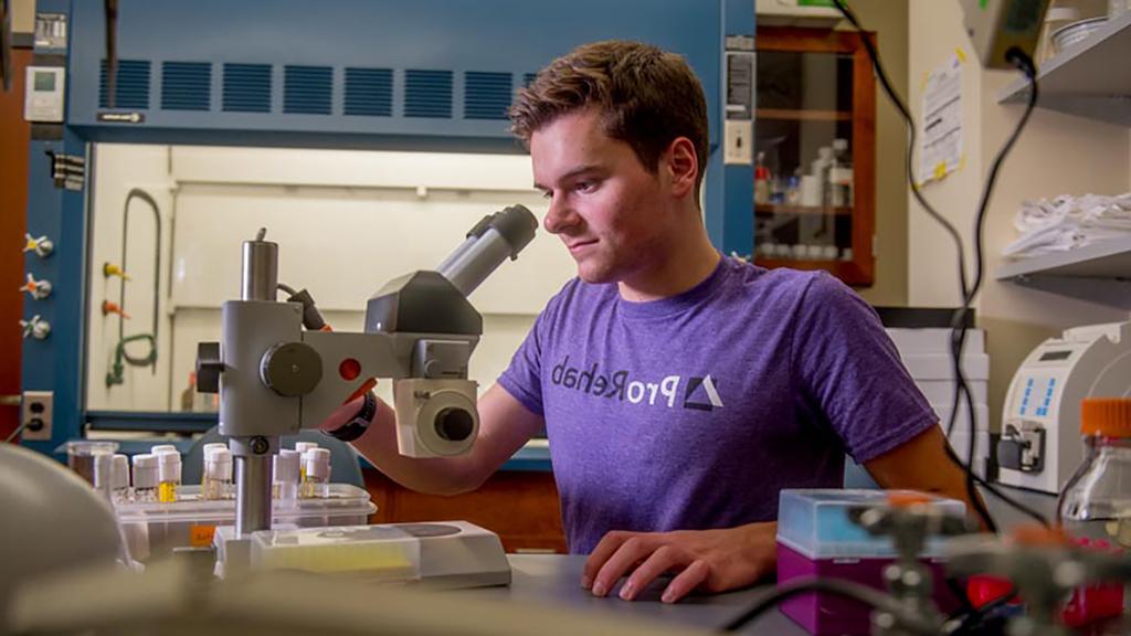 Biology student with microscope in ProRehab t-shirt